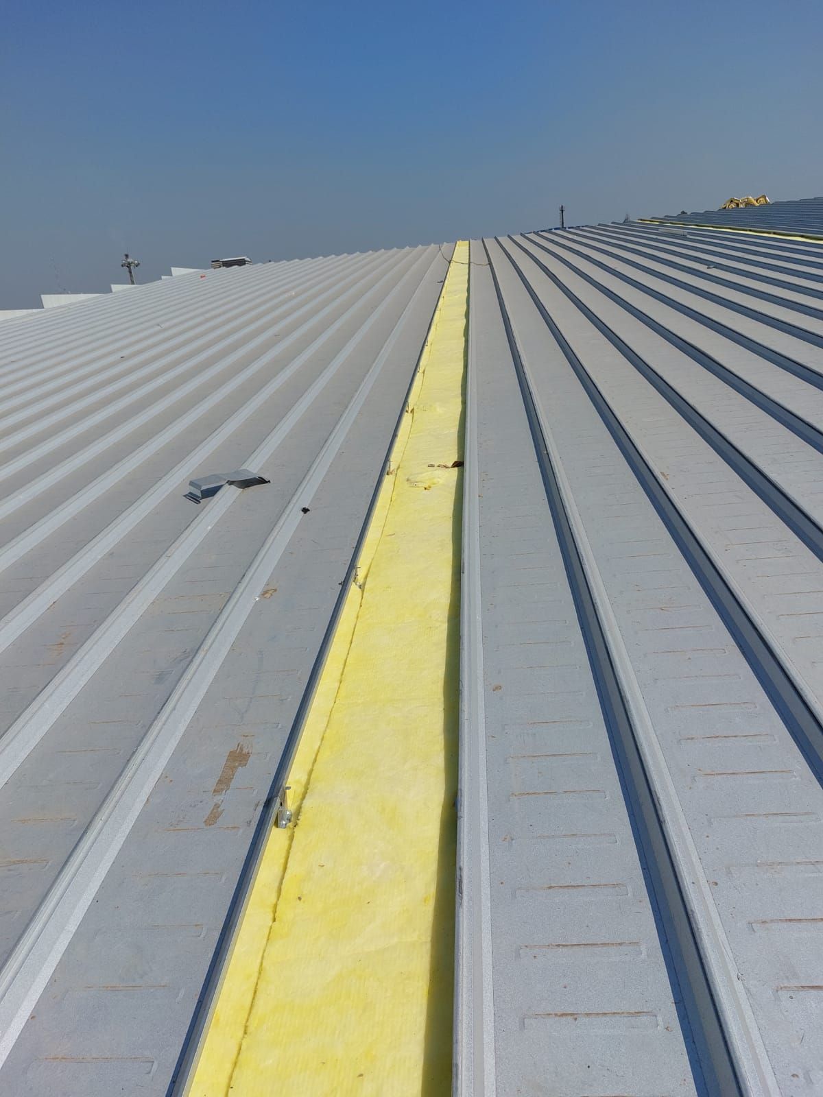 Strip of yellow insulation running between two rows of clip lock sheets