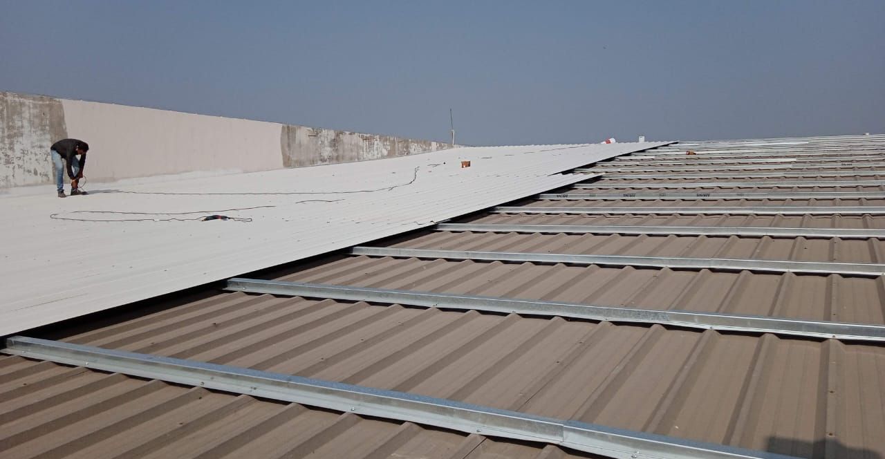 New roof sheet being fixed over an existing corrugated roof on galvanised sub-framing