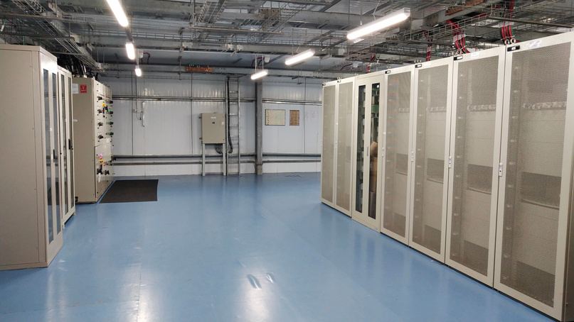 Equipment hall with rows of perforated-door racks and overhead cable trays