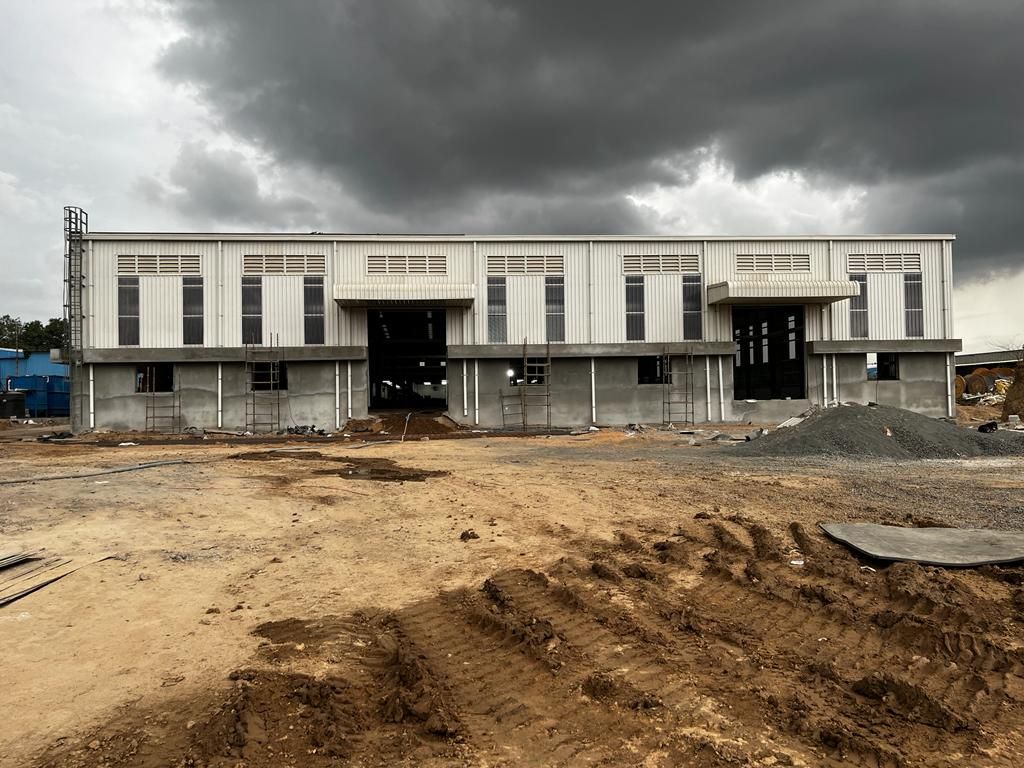 Completed PEB factory shell under dark monsoon clouds