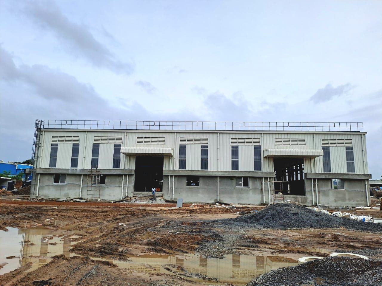 Front of a newly built PEB factory with louvres, windows, two loading entrances and a roof walkway rail