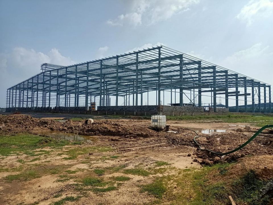 Steel portal frames of a large pre-engineered building standing on an open site