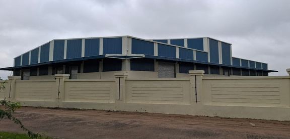 Completed blue and white pre-engineered warehouse behind a boundary wall