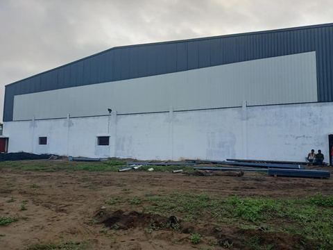 Side elevation of a warehouse with grey wall cladding and a dark blue roof band