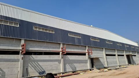 Long warehouse with profiled cladding above a concrete plinth and loading bays