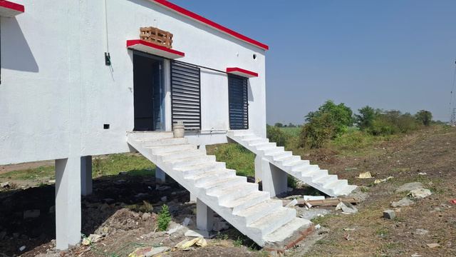 Raised white relay hut with concrete stairs near a railway line