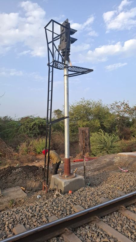 Colour-light railway signal on a steel post with a ladder and platform beside the track