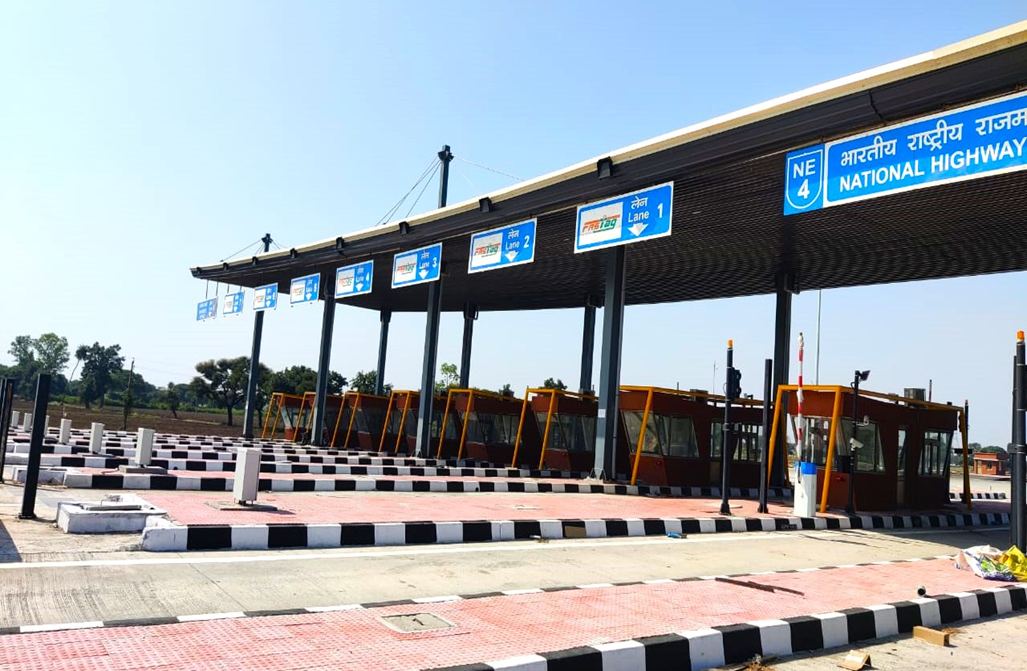 Multi-lane highway toll plaza with a canopy, lane signs and toll booths