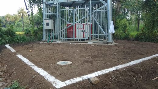 Base of a telecom tower with equipment enclosure and marked earthing area